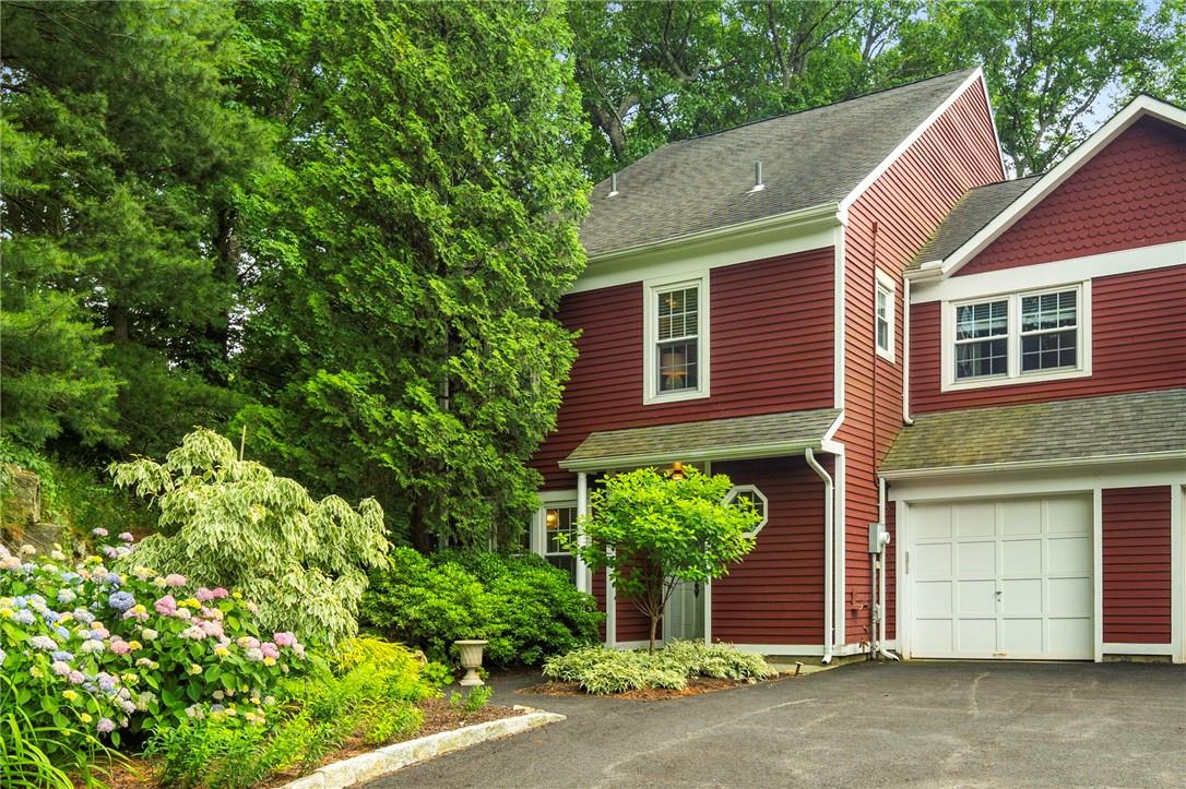 View of front of house featuring a garage with direct access into corner unit, slate walkway and garden path to patio