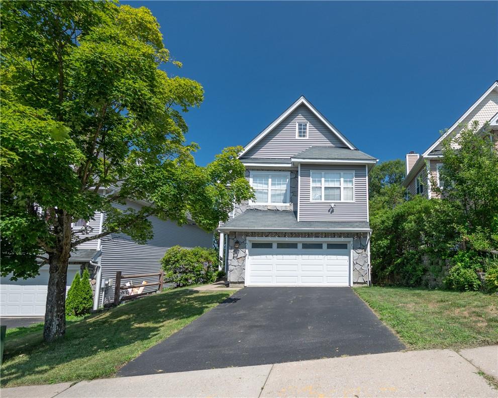 View of front of property featuring a garage and a front lawn