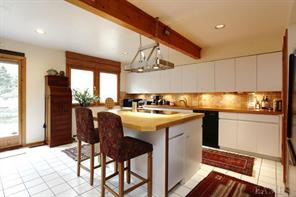 VIEW TO KITCHEN WITH EXTENSIVE STORAGE, NEW BOSCH APPLIANCES, TUMBLED STONE BACKSPLASH AND CUSTOM COUNTER TOPS.