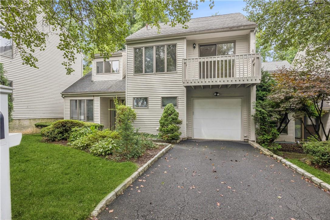 View of front of house featuring a balcony, a garage, and a front yard