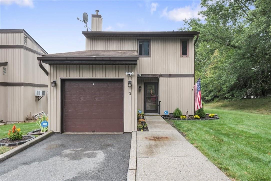 View of front of home featuring a garage, an AC wall unit, and a front yard