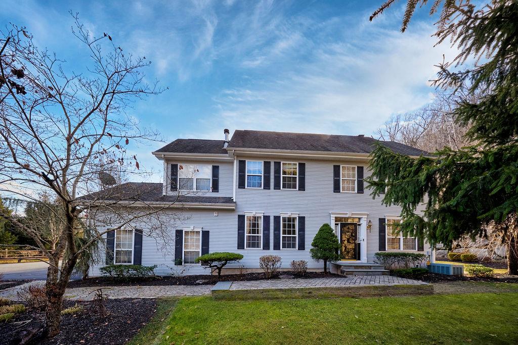 Colonial house with central AC unit and a front lawn