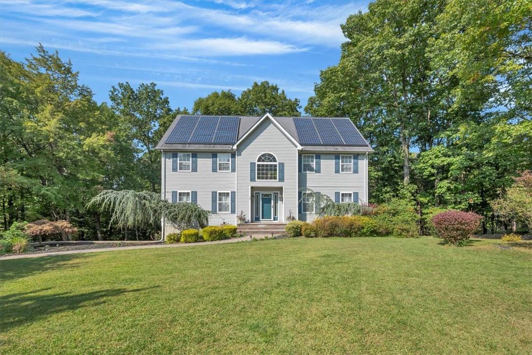 Colonial house with a front yard and solar panels