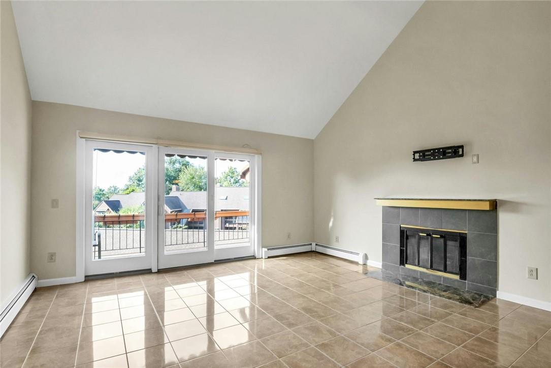 Unfurnished living room featuring high vaulted ceiling, a baseboard heating unit, a tile fireplace, and light tile patterned floors