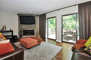 Stunning Stone floor to ceiling fireplace sets the tone for this spacious bright living room space featuring recessed lighting and doors to private deck with tree top views.  TV wall bracket stays; additional stones if bracket removed.