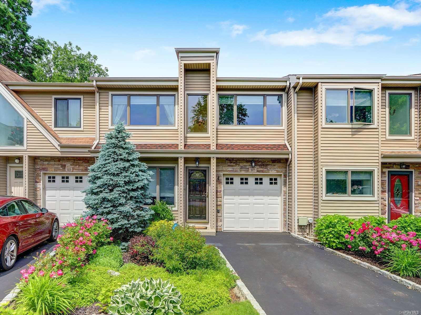 Front of the home with colorful plantings and trees