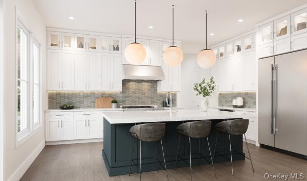 Kitchen with high end fridge, light countertops, under cabinet range hood, and a healthy amount of sunlight