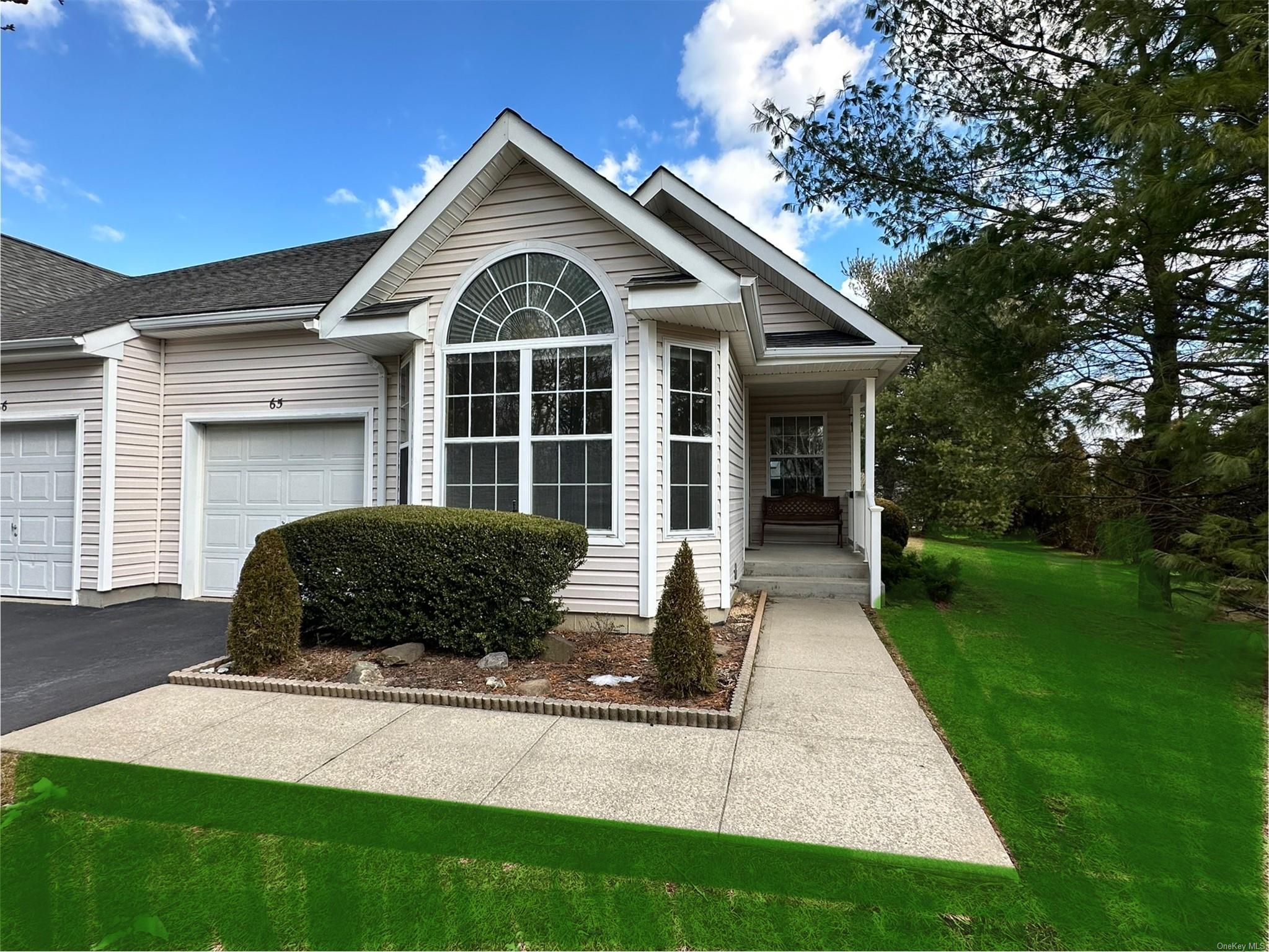 View of front of home featuring a garage, a front lawn, and covered porch