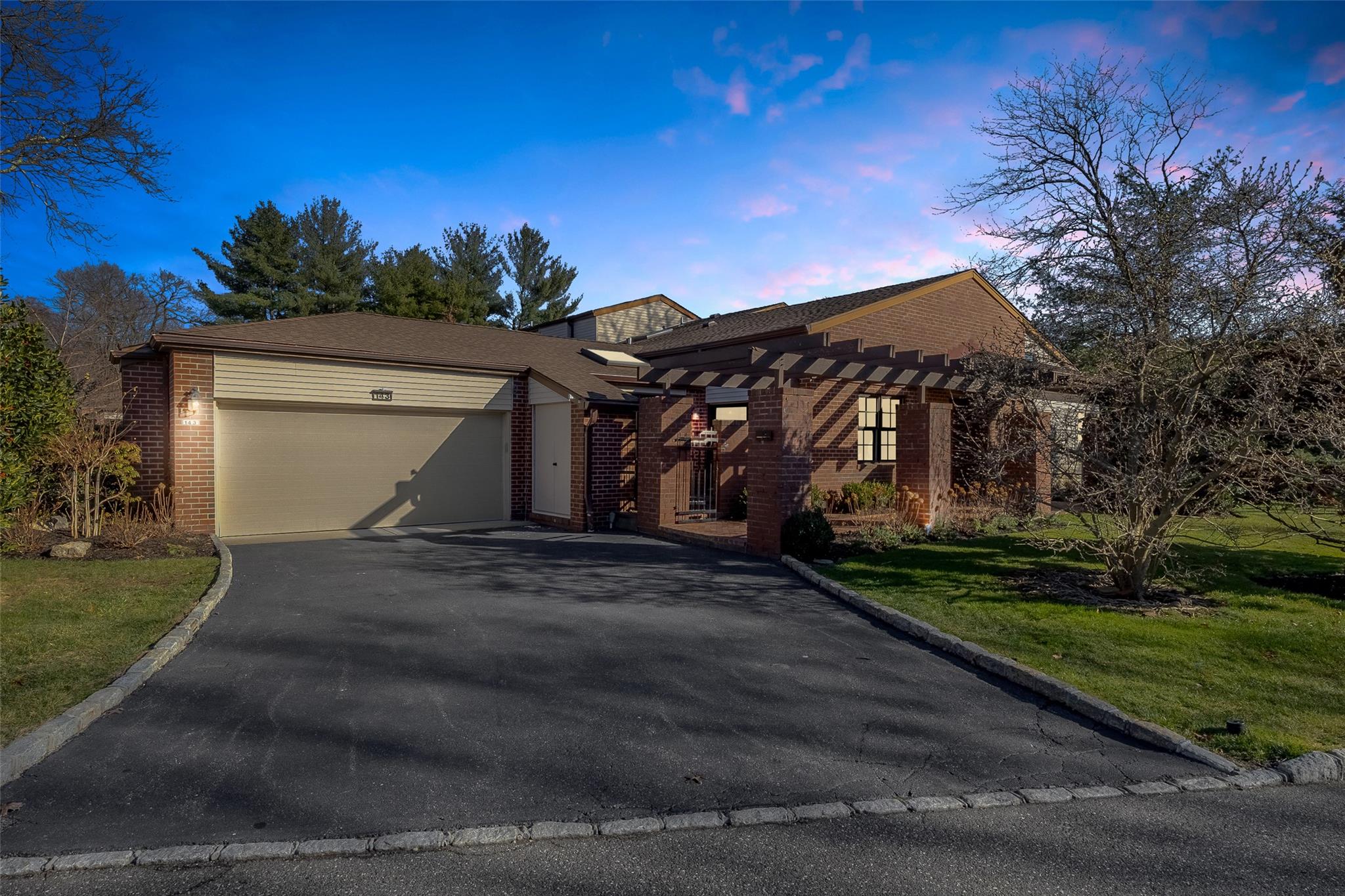 View of front facade featuring brick siding, aphalt driveway, a garage, a yard, and a pergola