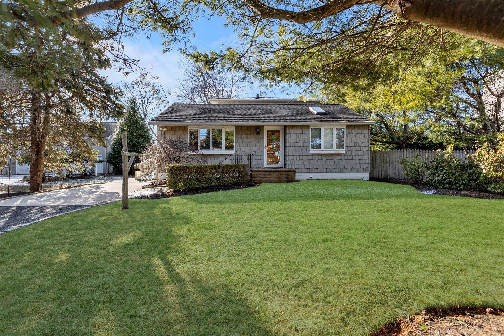 View of front facade featuring driveway and a shingled roof