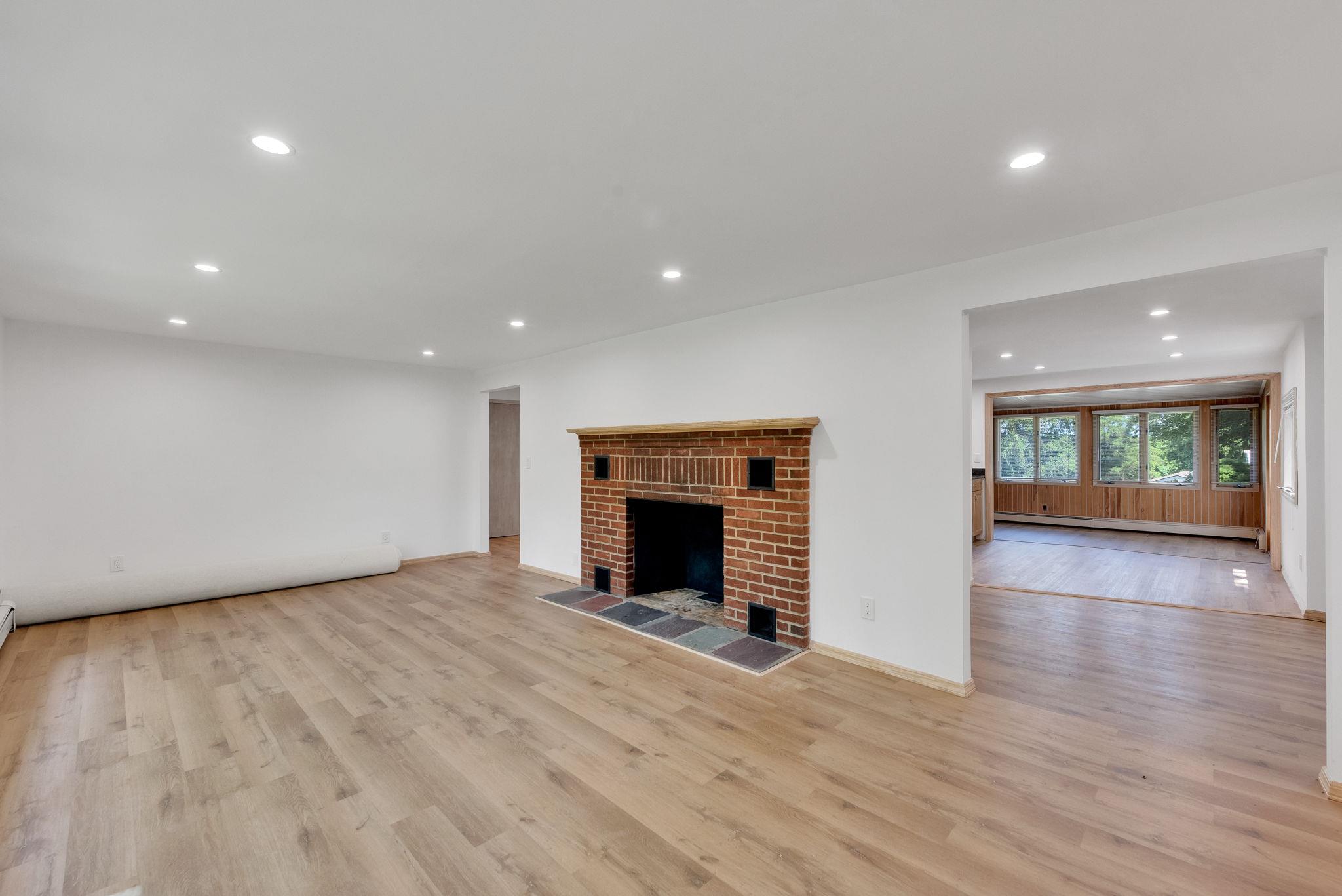 Unfurnished living room with light wood-type flooring, a baseboard radiator, and a tiled fireplace