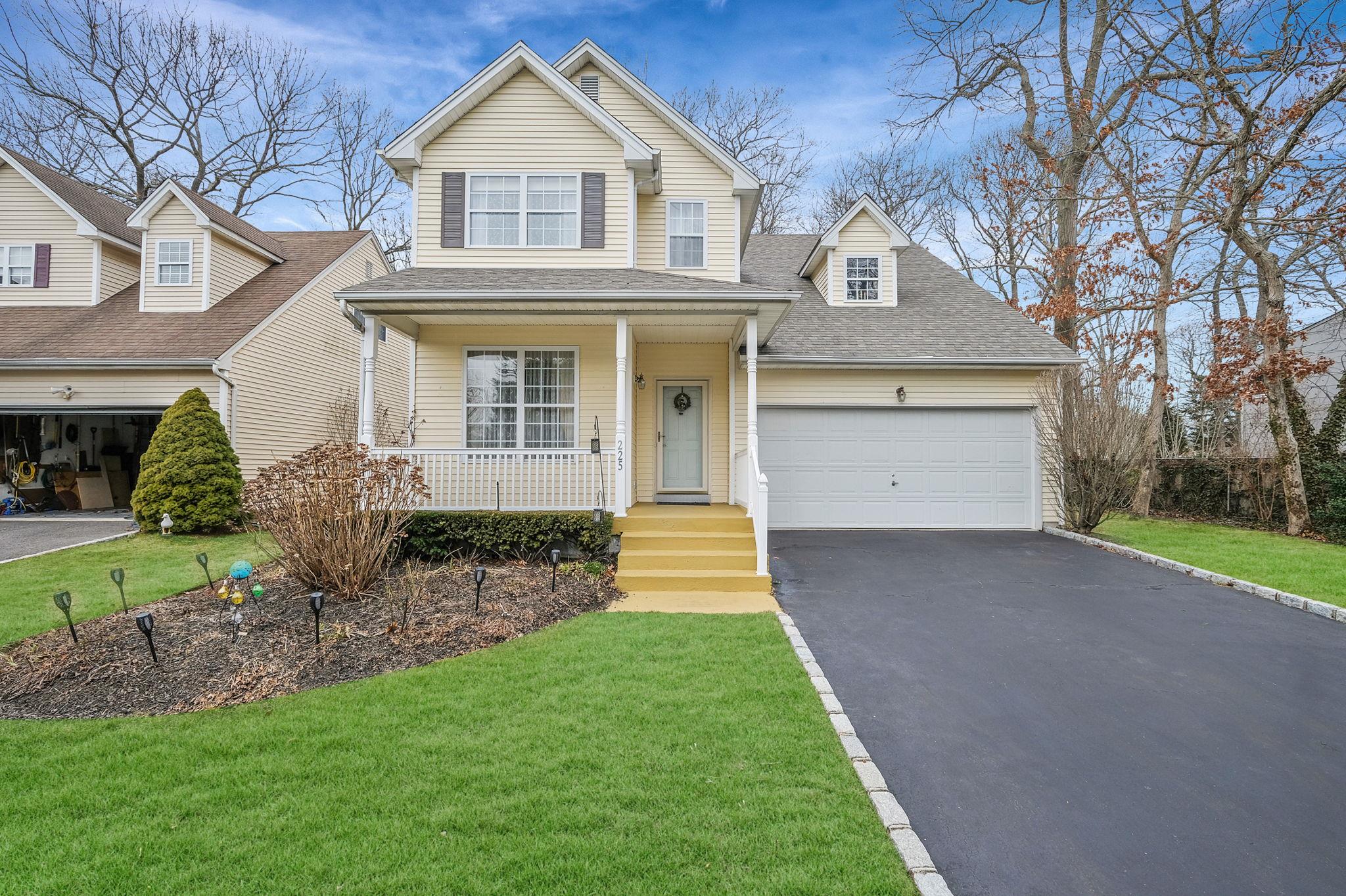 View of front of property with a porch, a front lawn, and a garage