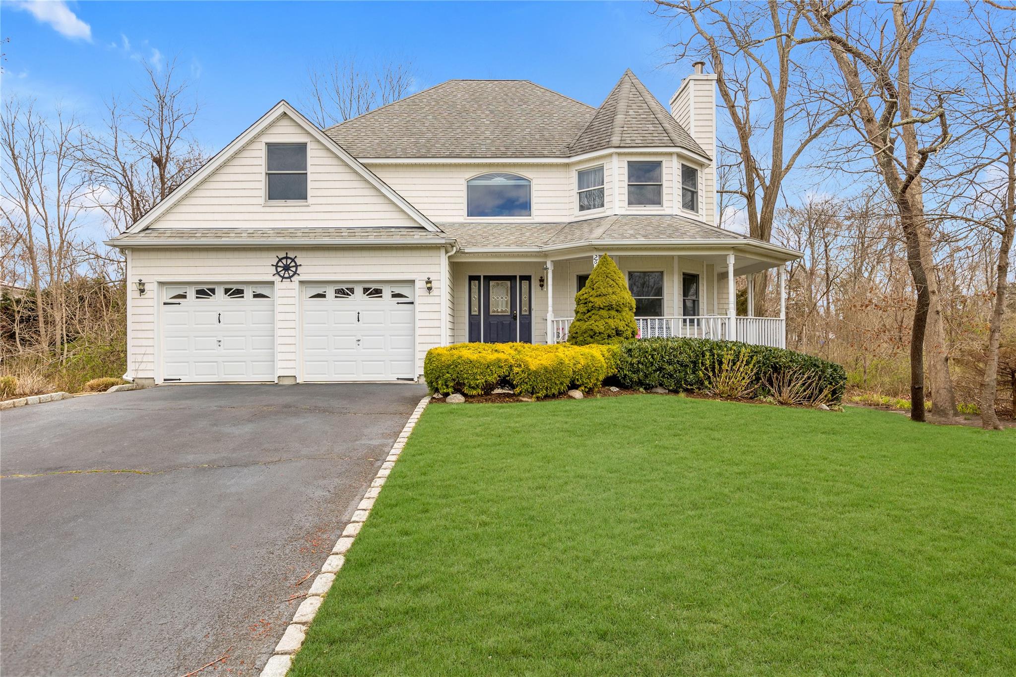 View of front facade with a garage, a front lawn, and covered porch