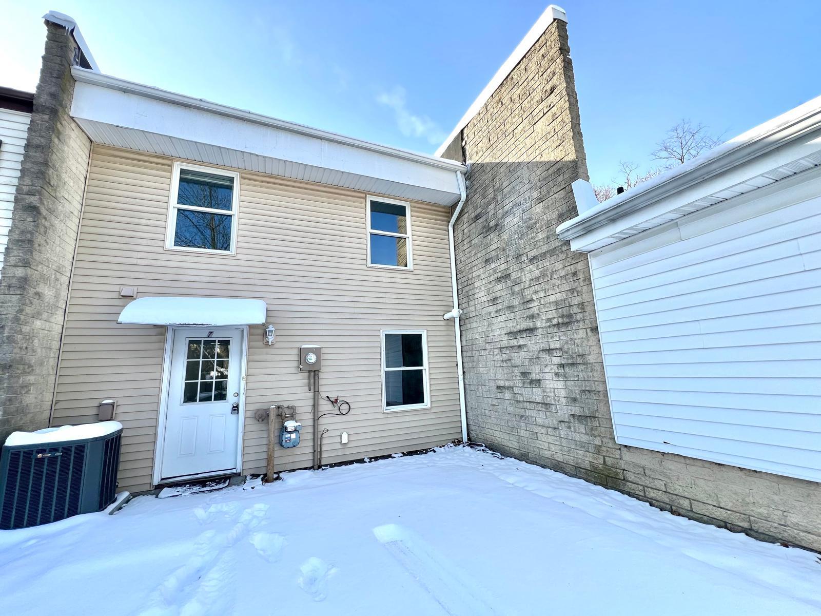 Snow covered rear of property with central air condition unit