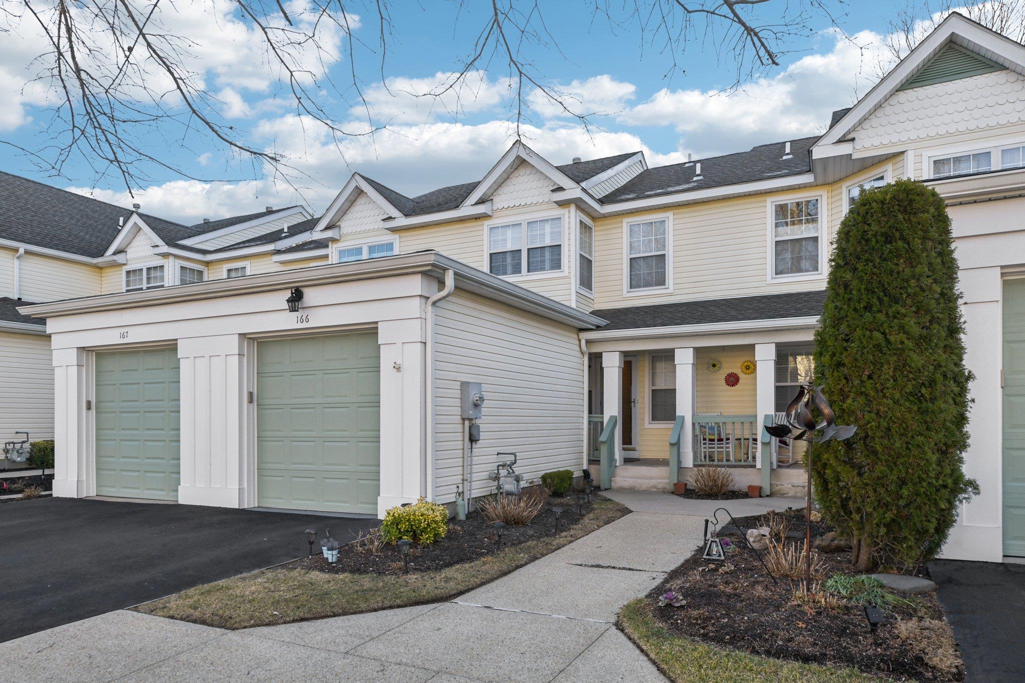 View of property with a porch, an attached garage, and driveway