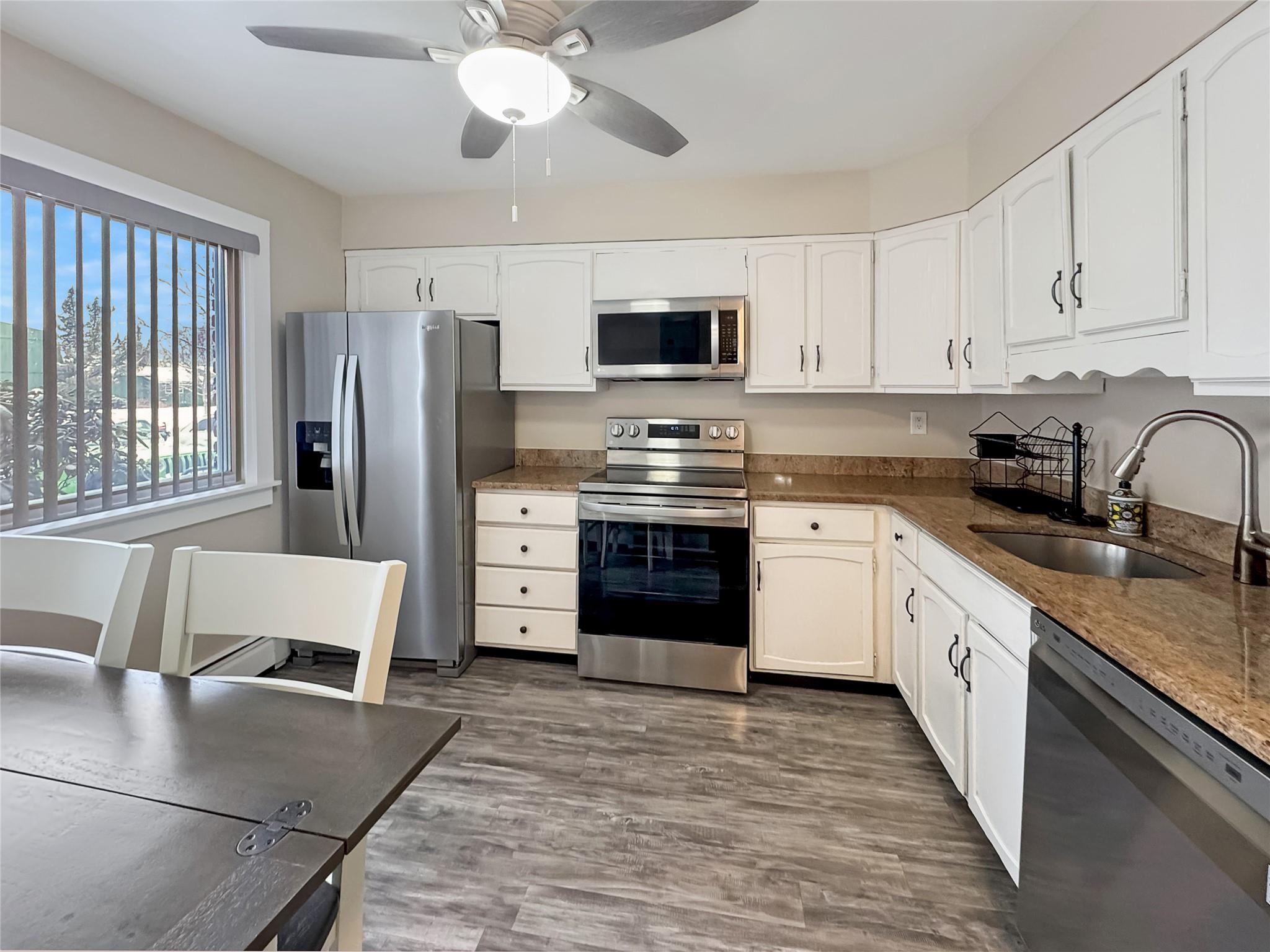 Kitchen featuring sink, dark wood-type flooring, stainless steel appliances, and white cabinets