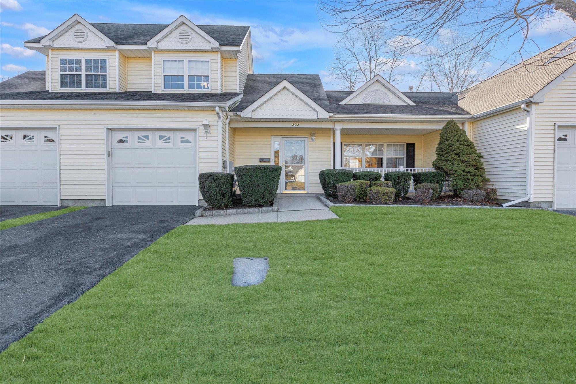 View of front of property with a porch, a garage, and a front lawn
