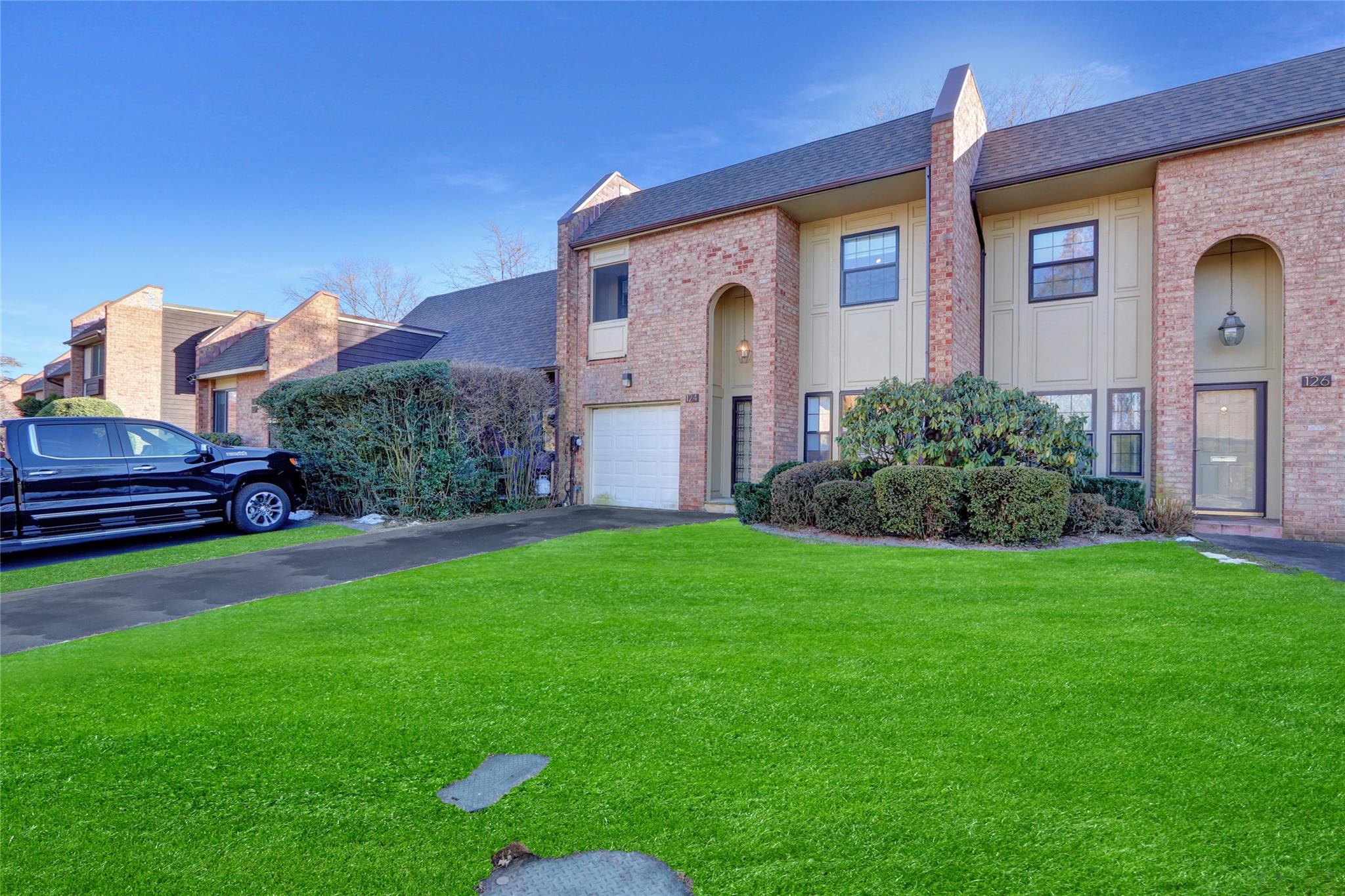 View of property featuring a garage and a front lawn