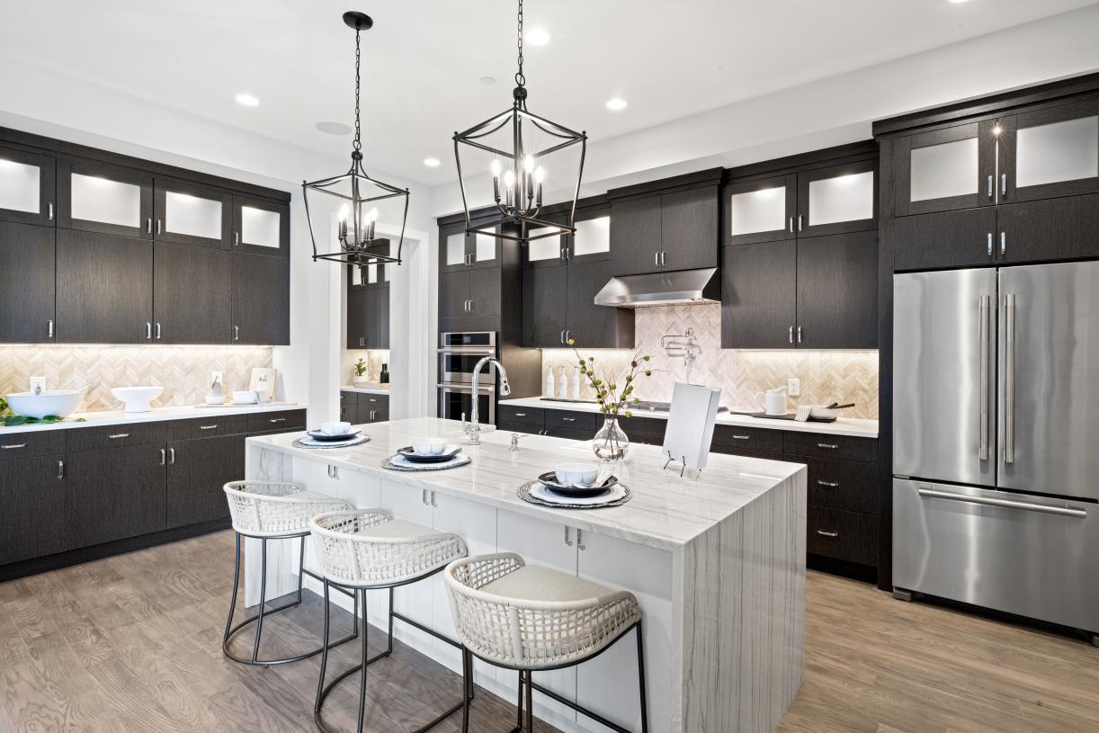 Kitchen with a kitchen breakfast bar, hanging light fixtures, stainless steel appliances, a center island with sink, and light hardwood / wood-style flooring