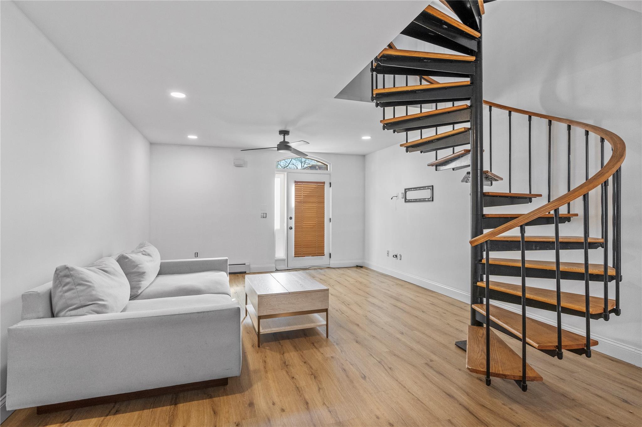 Living room featuring ceiling fan, a baseboard radiator, and light hardwood / wood-style floors