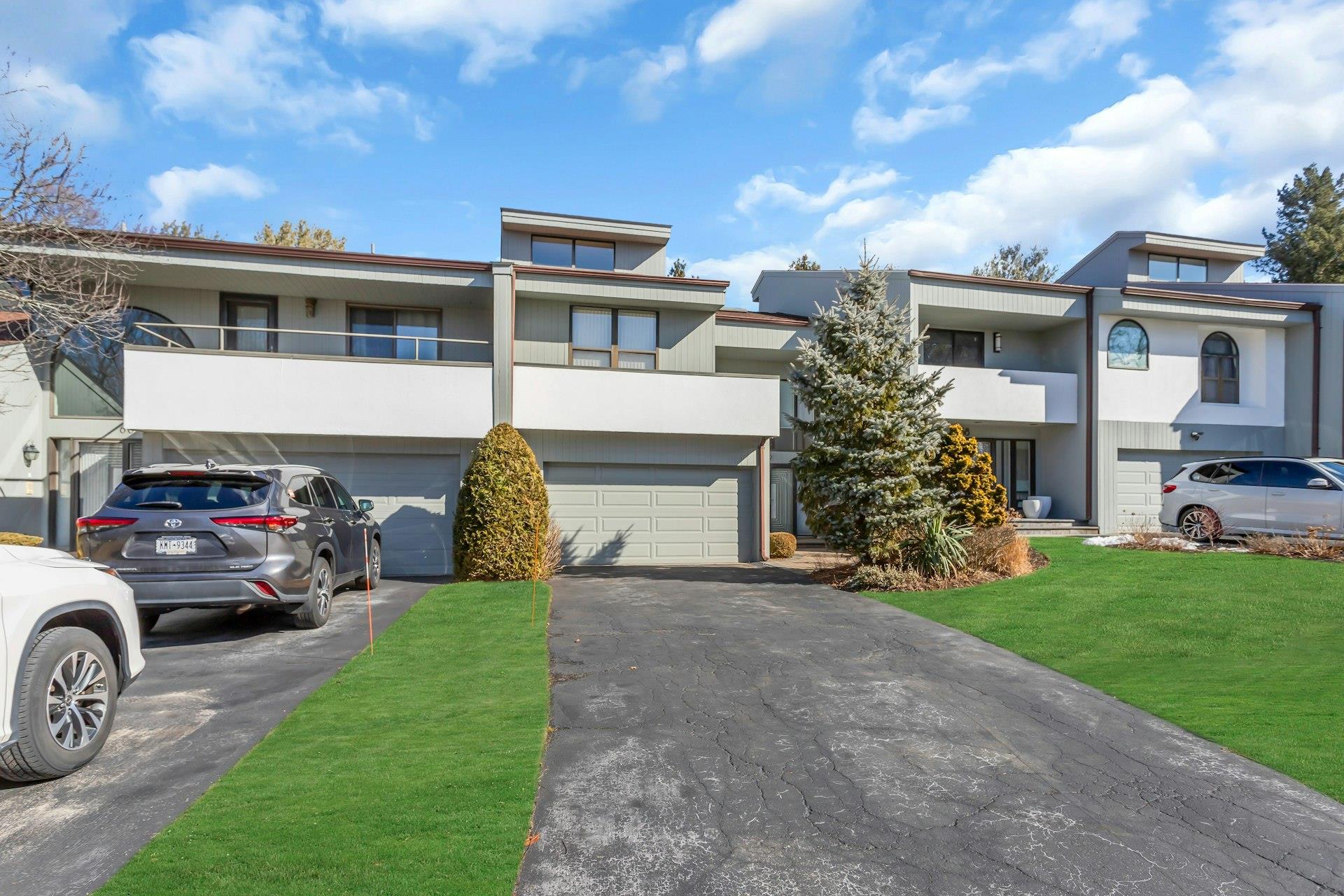 View of front of property featuring a garage, a balcony, and a front lawn