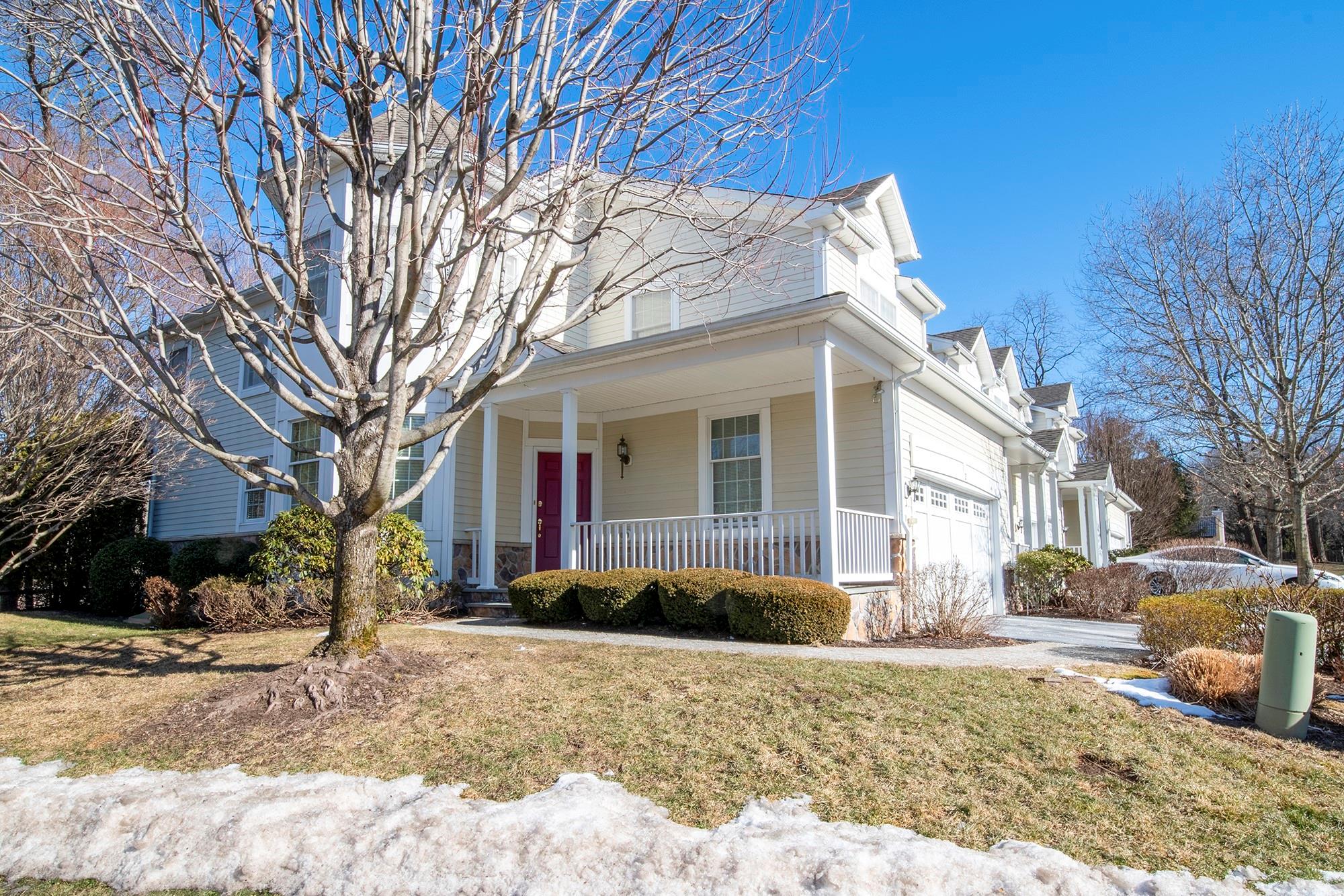 View of front of home with a garage, a front yard, and covered porch