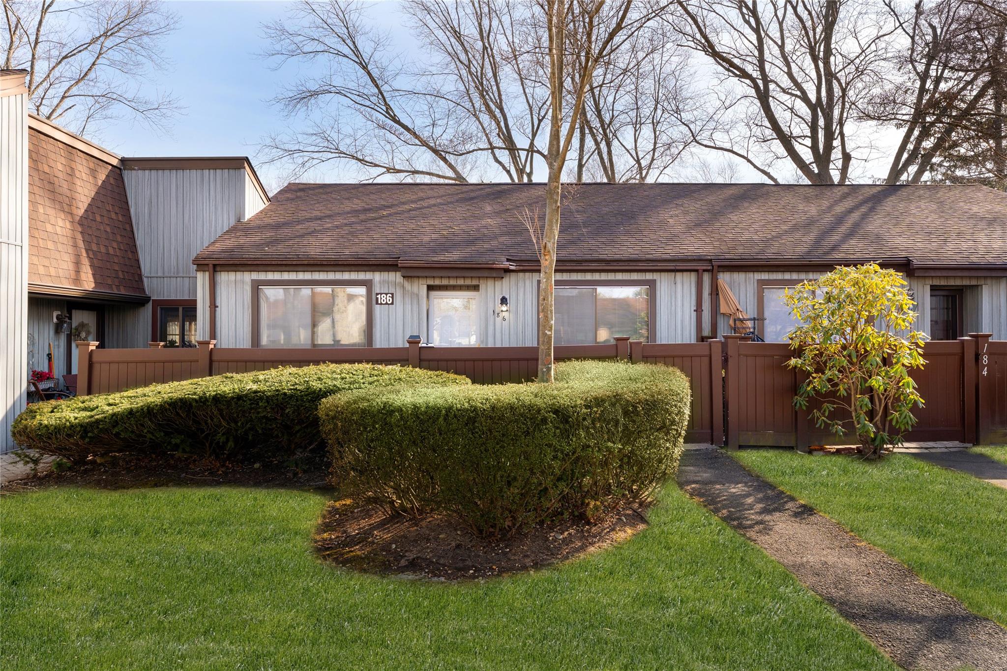 View of front of property featuring a shingled roof, fence, and a front lawn
