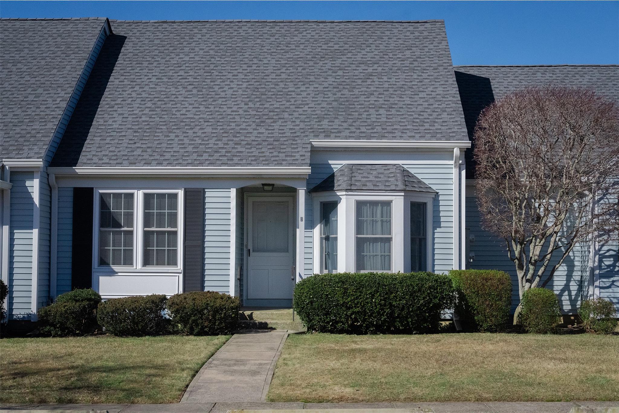 View of front facade with roof with shingles and a front yard
