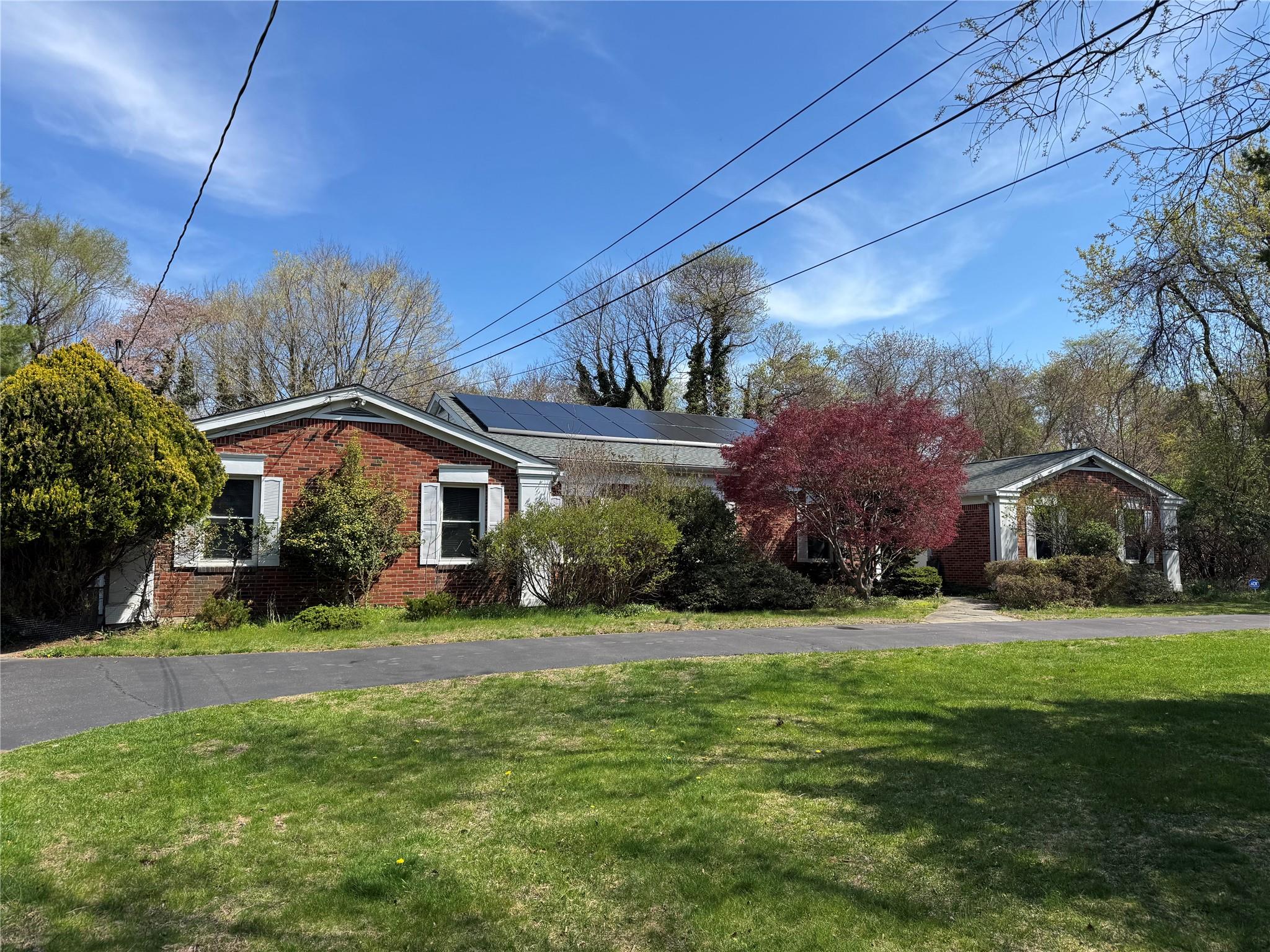 View of front of property featuring roof mounted solar panels, brick siding, and a front lawn
