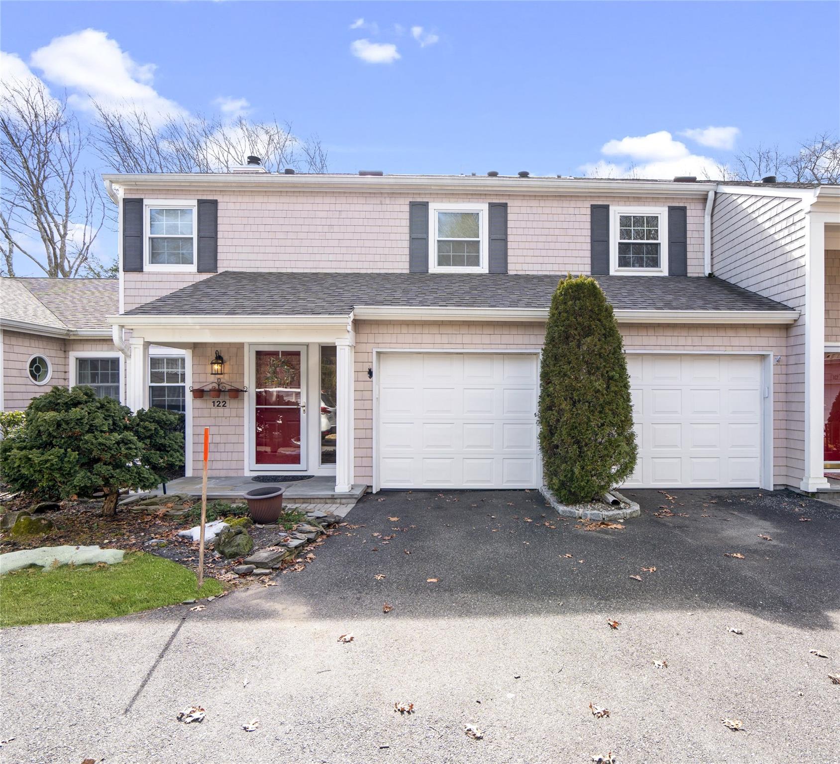 View of front facade with a shingled roof, driveway, and a garage