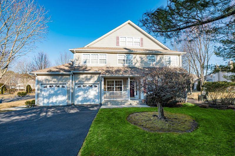 View of front of property featuring an attached garage, a porch, aphalt driveway, and a front yard
