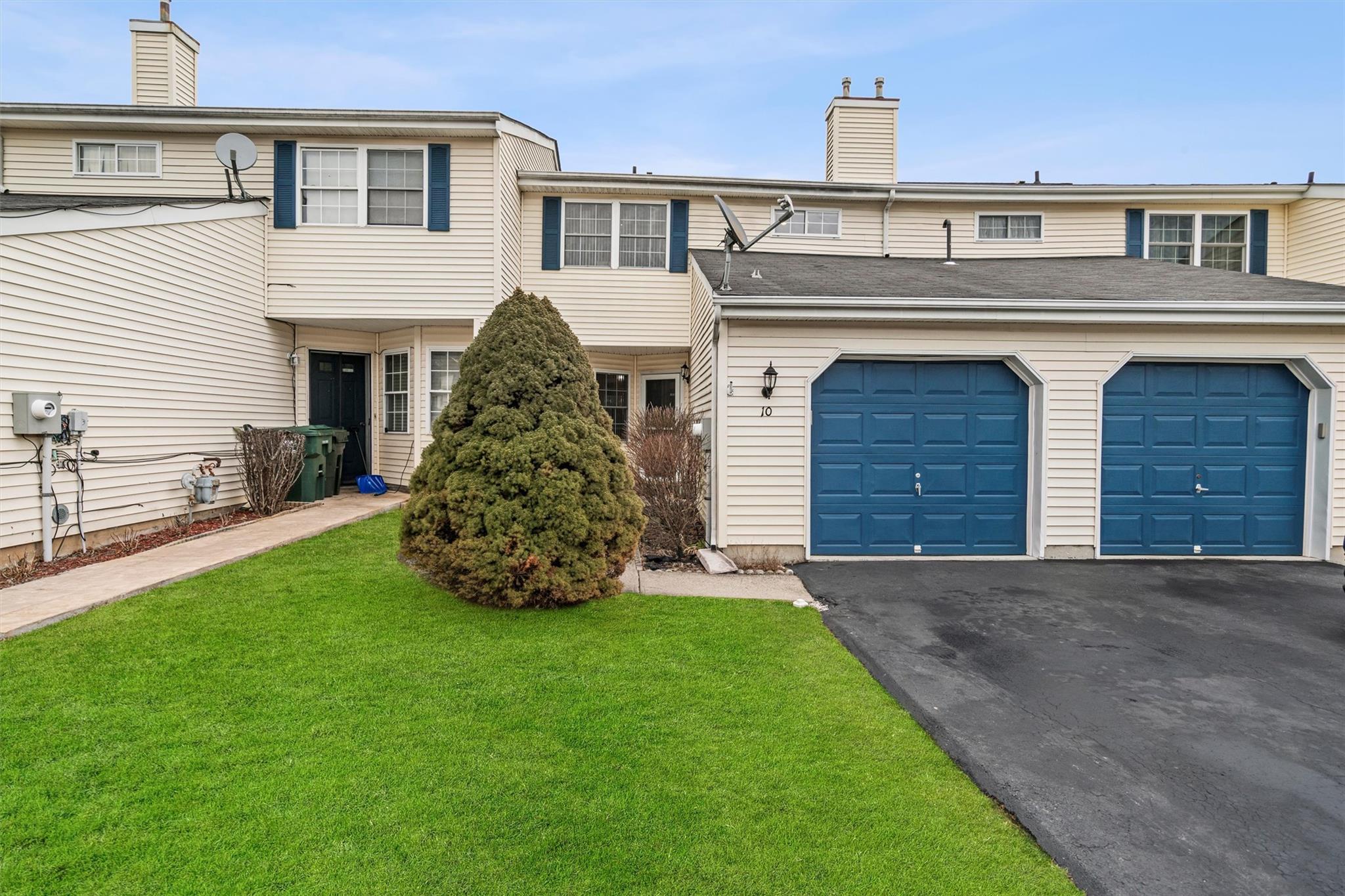 View of property featuring aphalt driveway, a garage, a chimney, and a front lawn