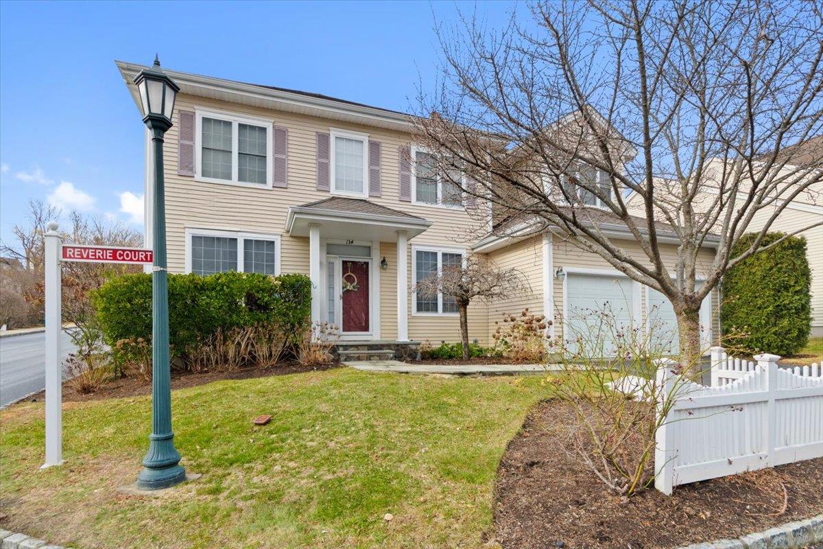View of front of home featuring an attached garage, fence, and a front lawn