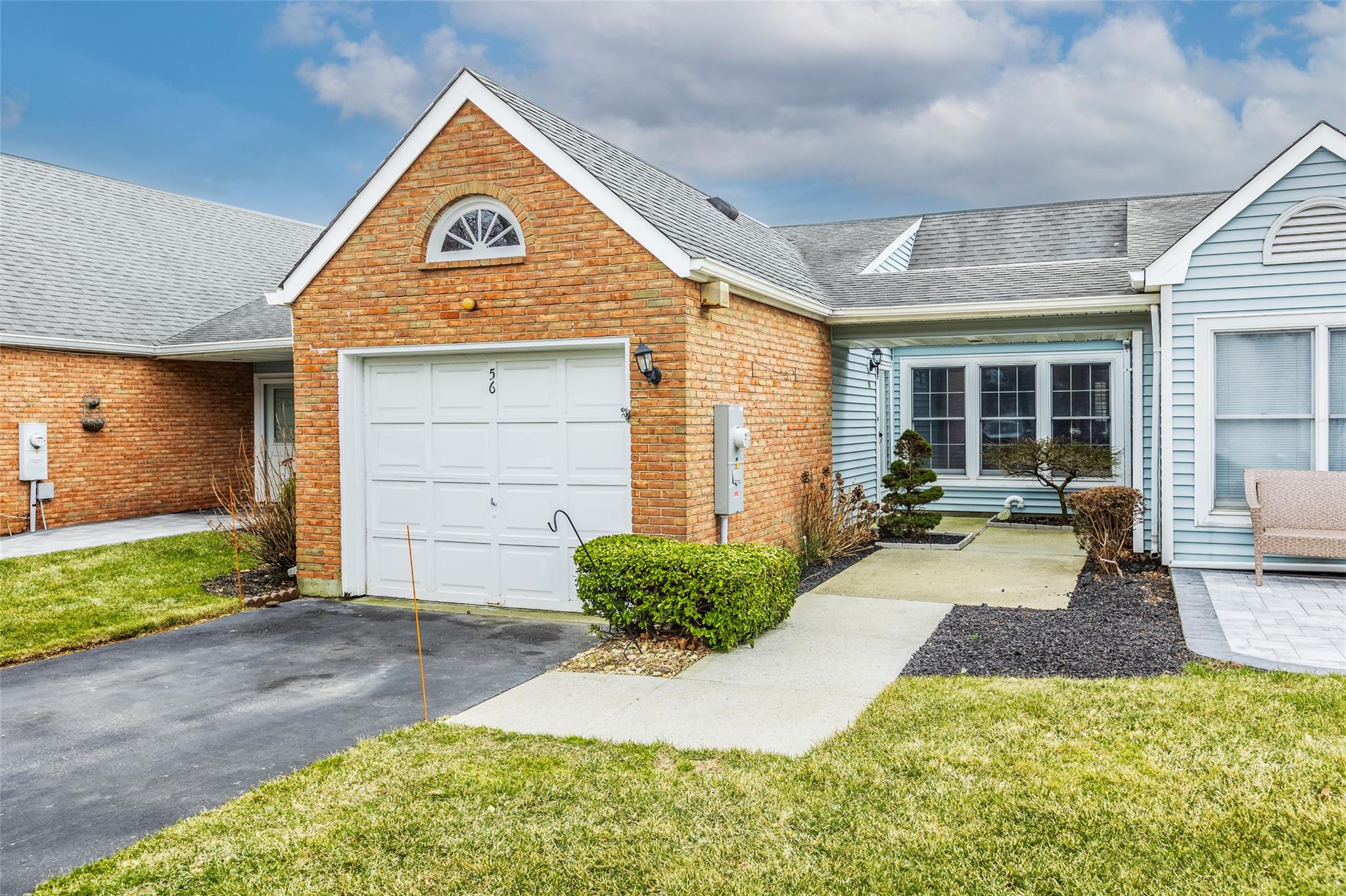 View of front of property with a garage, roof with shingles, aphalt driveway, and brick siding