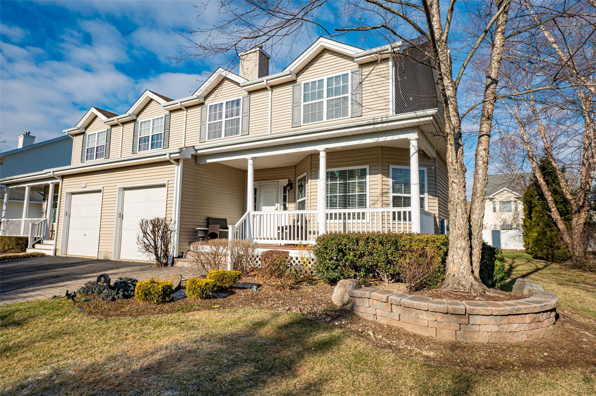 View of front of home with an attached garage, aphalt driveway, a chimney, and a porch