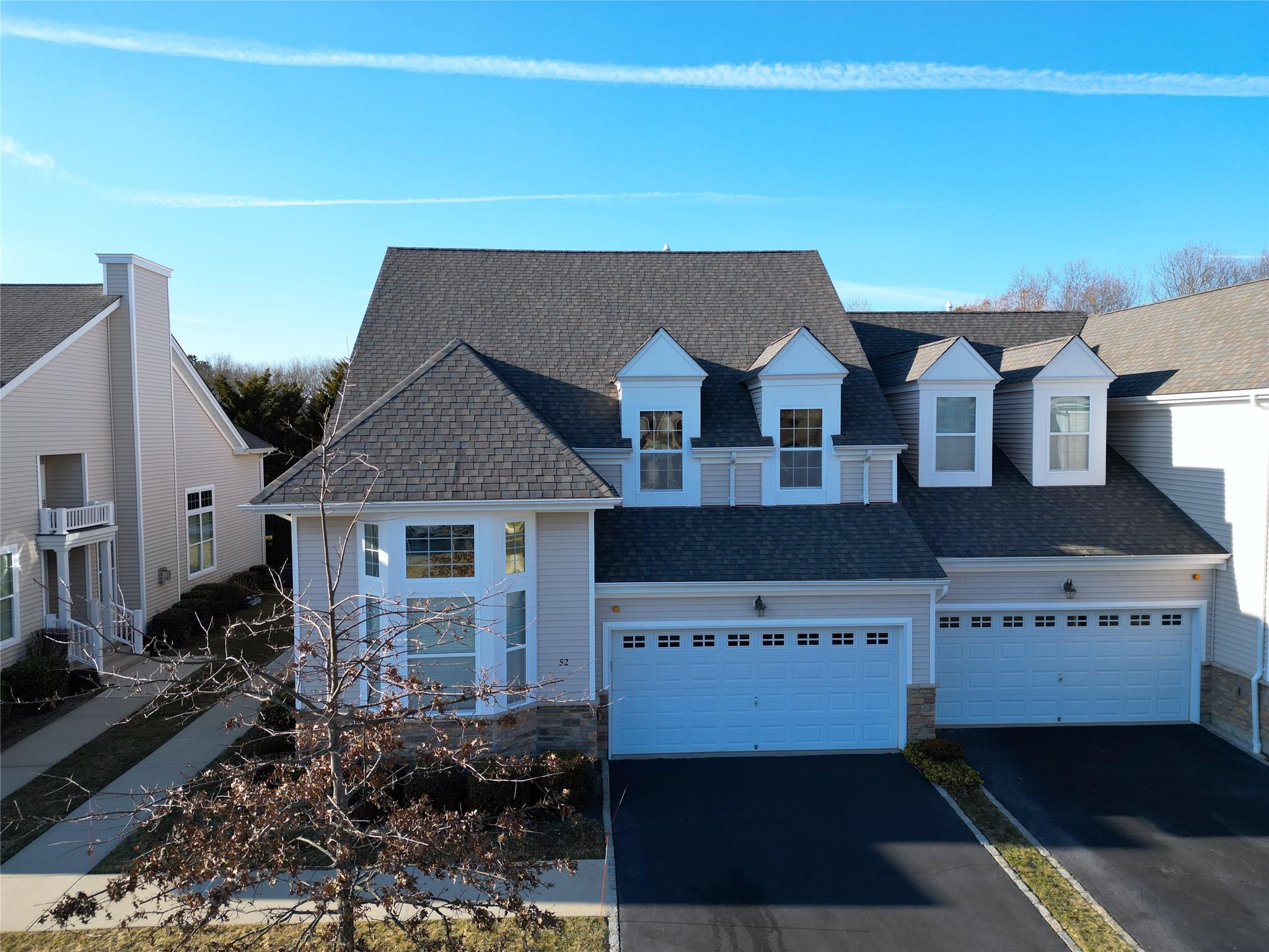 View of front of house featuring a garage, aphalt driveway, and roof with shingles