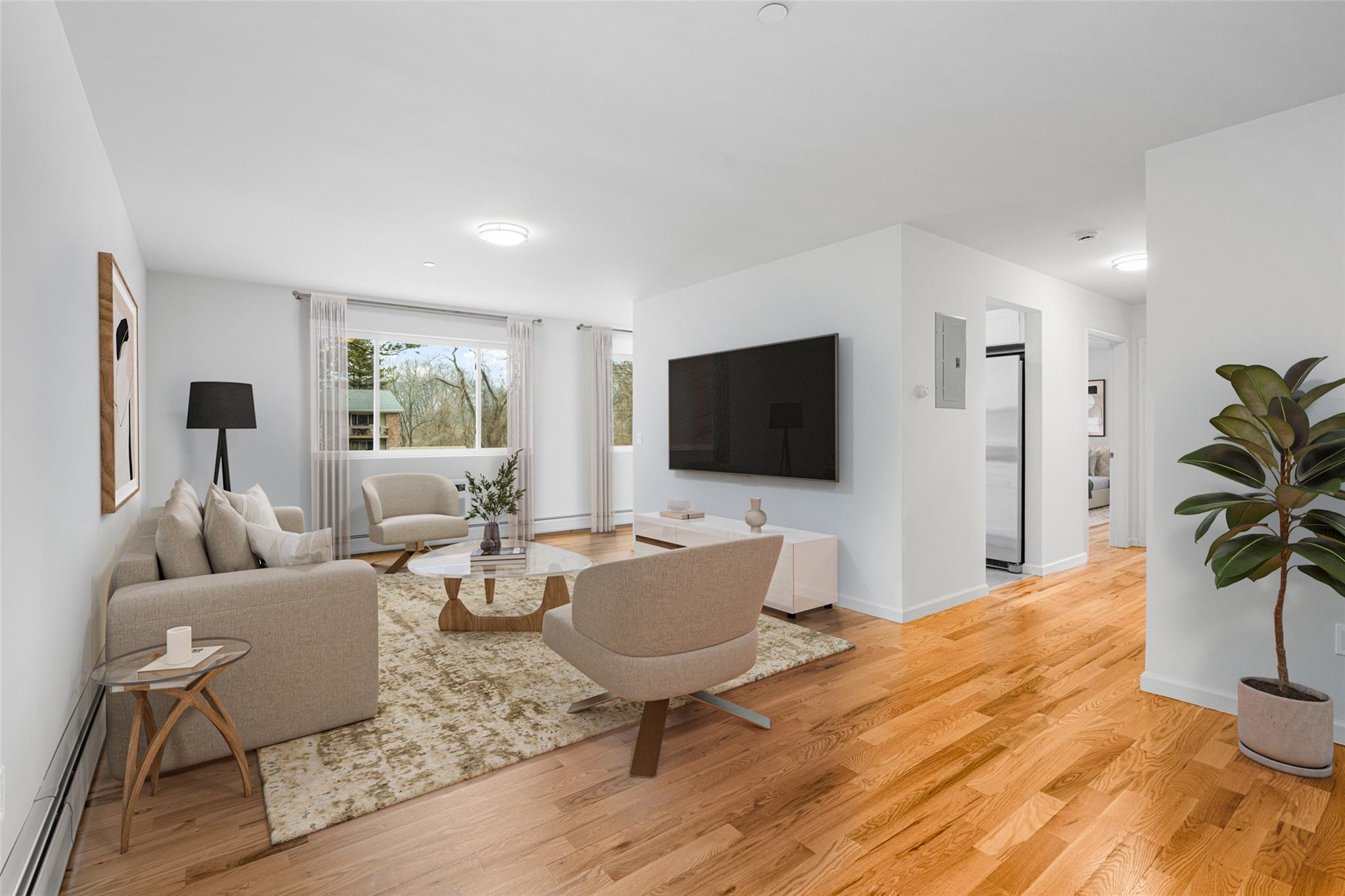 Virtually staged living area with baseboard heating, and light hardwood flooring