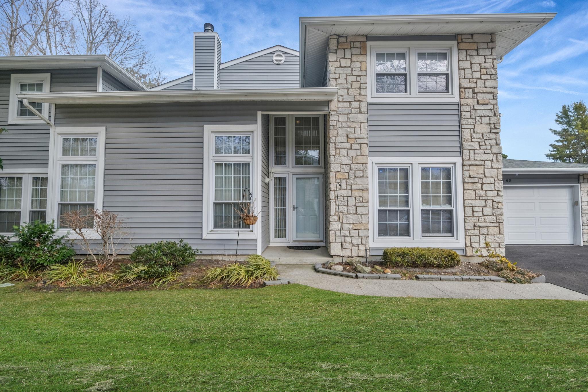 View of front of property featuring a front lawn, a garage, driveway, and a chimney