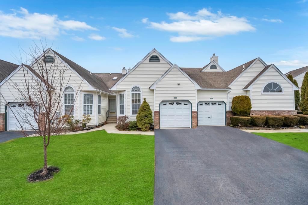 View of front of home featuring brick siding, driveway, a chimney, and a front yard