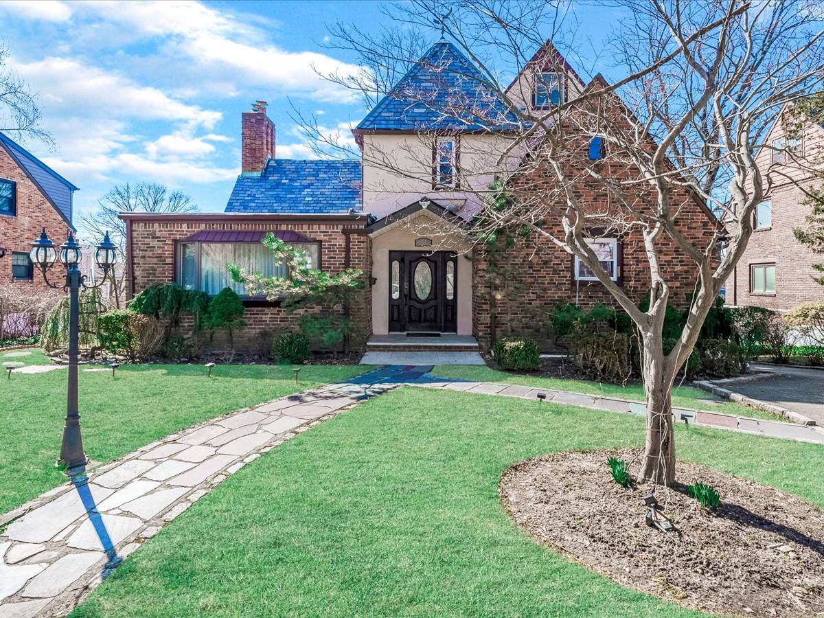 View of front of house featuring a front yard, a high end roof, brick siding, and a chimney