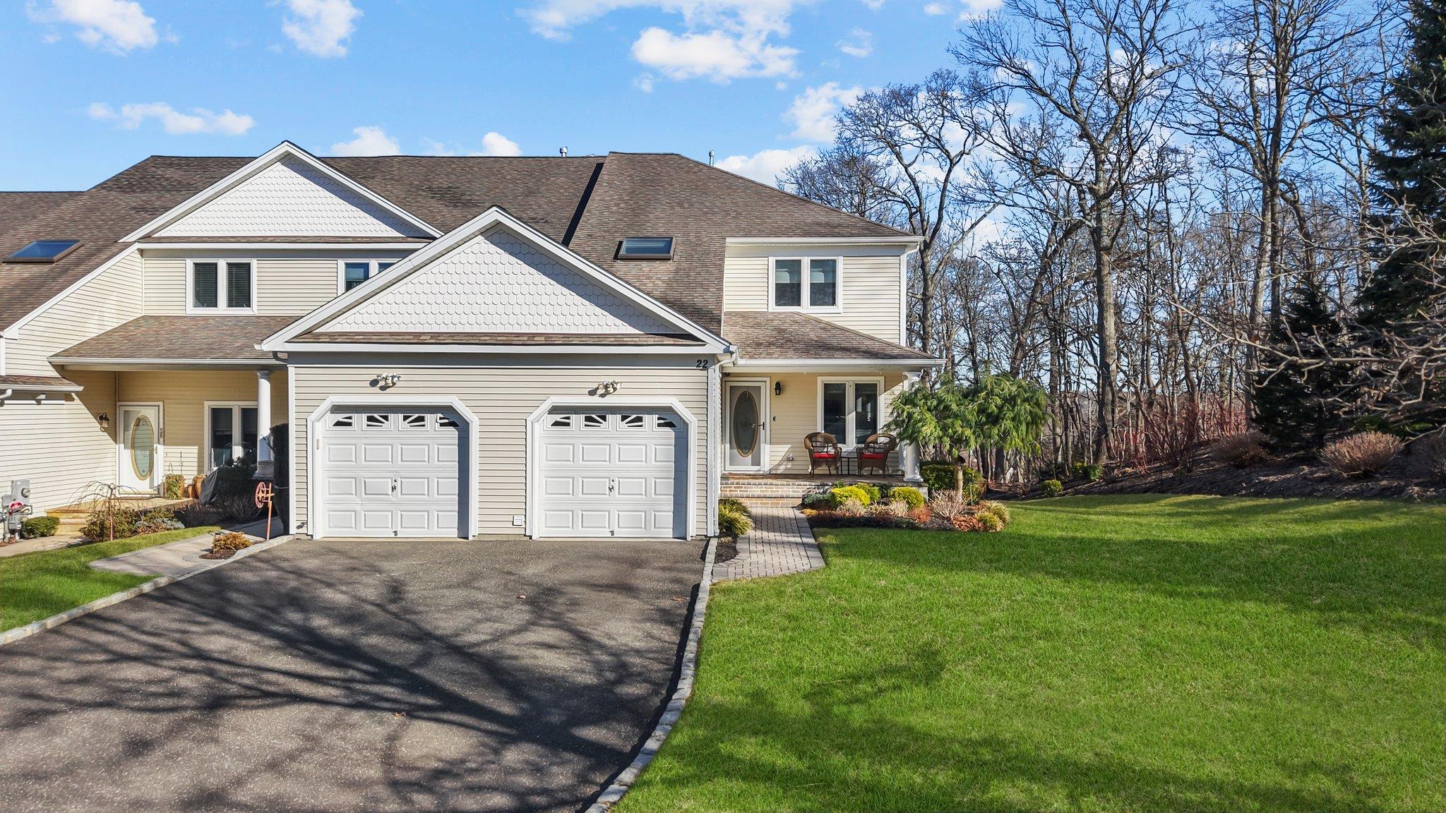 View of front of property with a shingled roof, aphalt driveway, a porch, a front yard, and a garage
