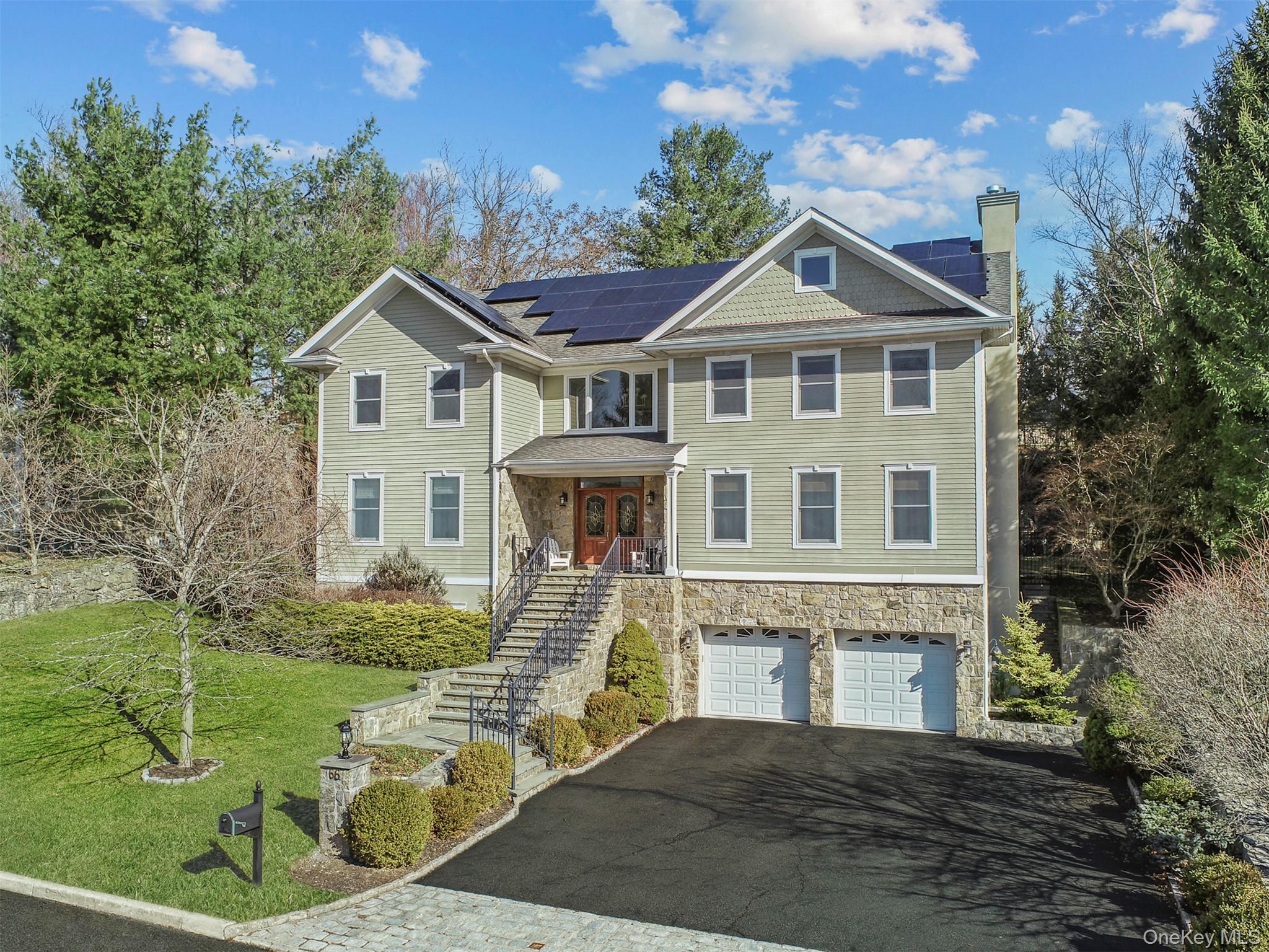 View of front of home with driveway, roof mounted solar panels, a front yard, a garage, and a chimney