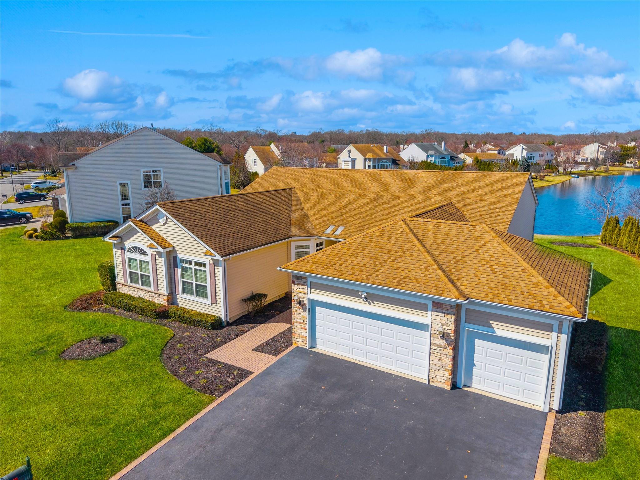 View of front facade featuring a front lawn, aphalt driveway, a residential view, a garage, and stone siding
