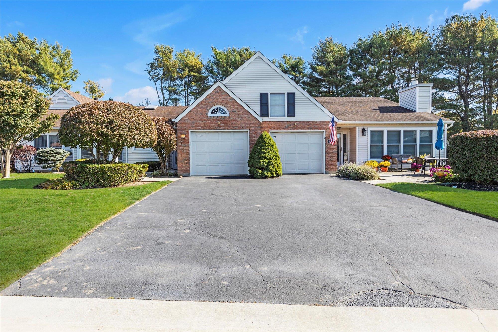View of front facade featuring driveway, a chimney, a front lawn, a garage, and brick siding