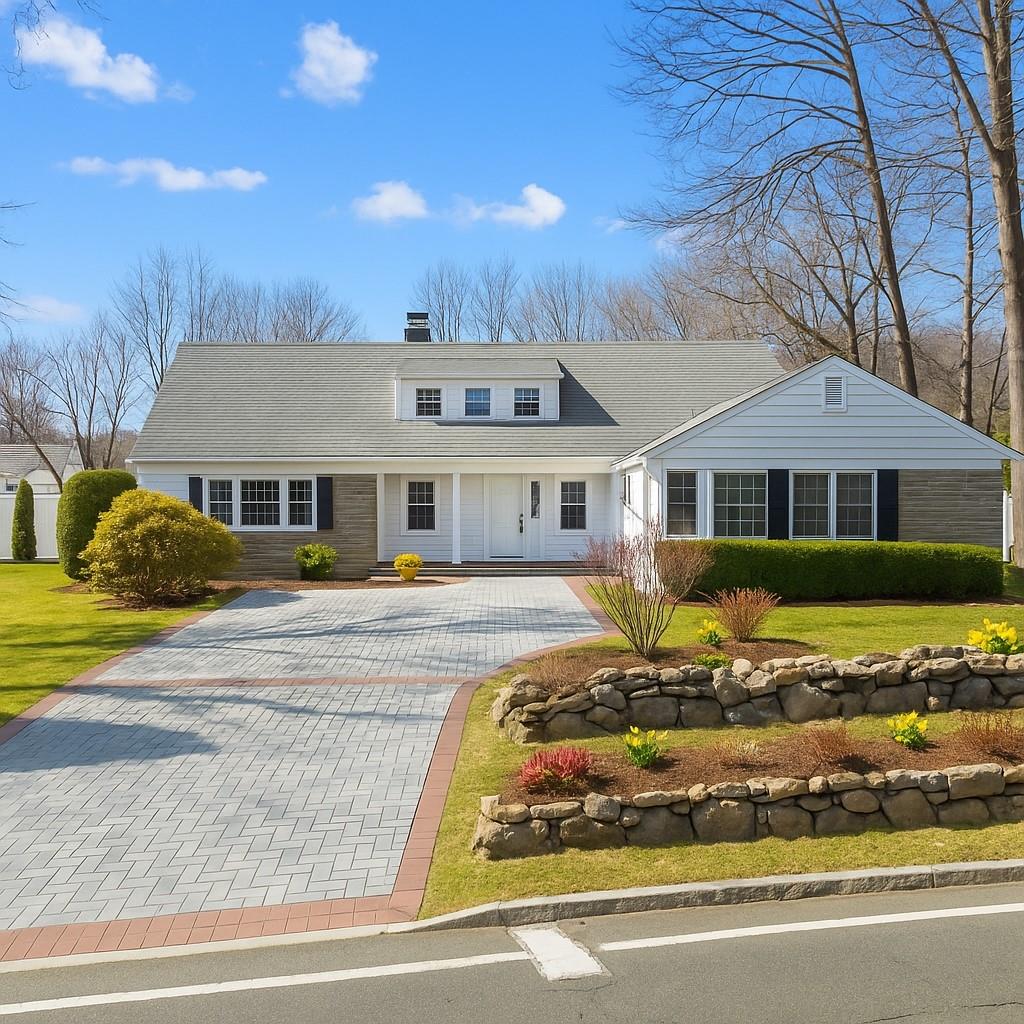 View of front of home featuring driveway, a chimney, and a front yard