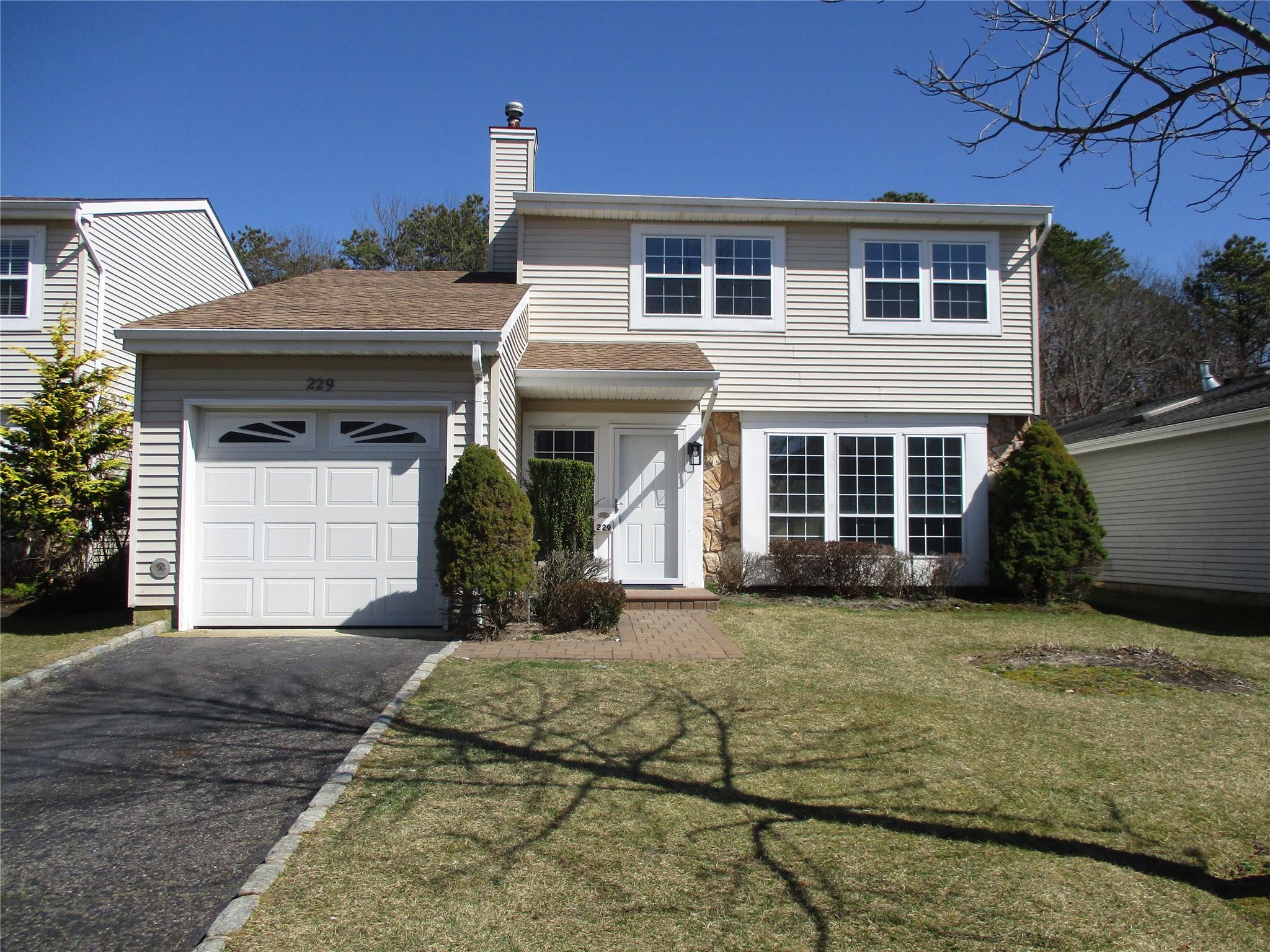 View of front of house featuring aphalt driveway, a garage, a front yard, and a chimney