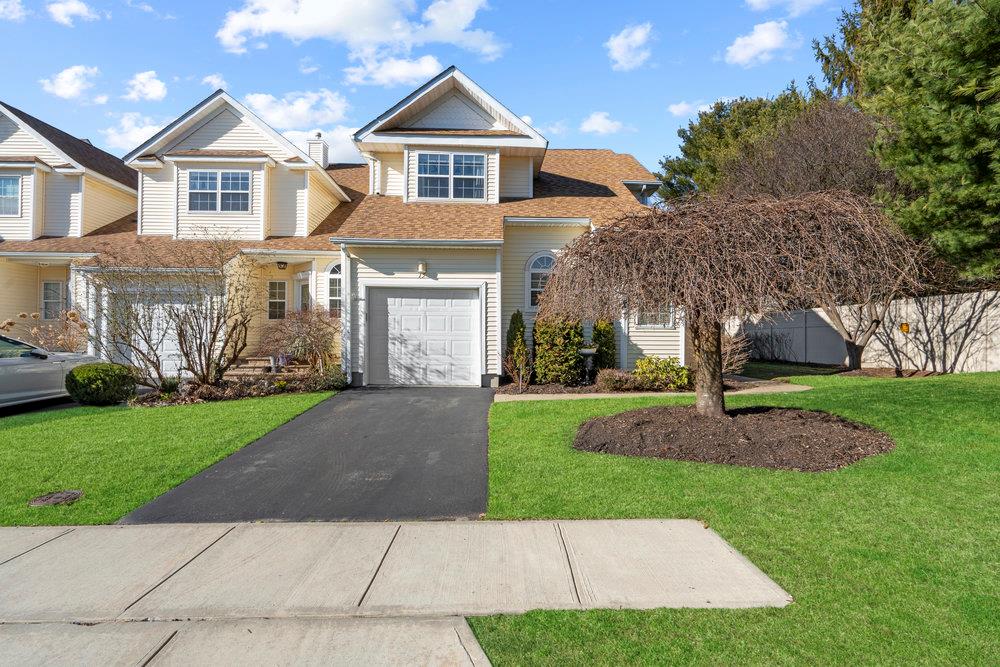 View of front of property with a front yard, fence, driveway, and a shingled roof