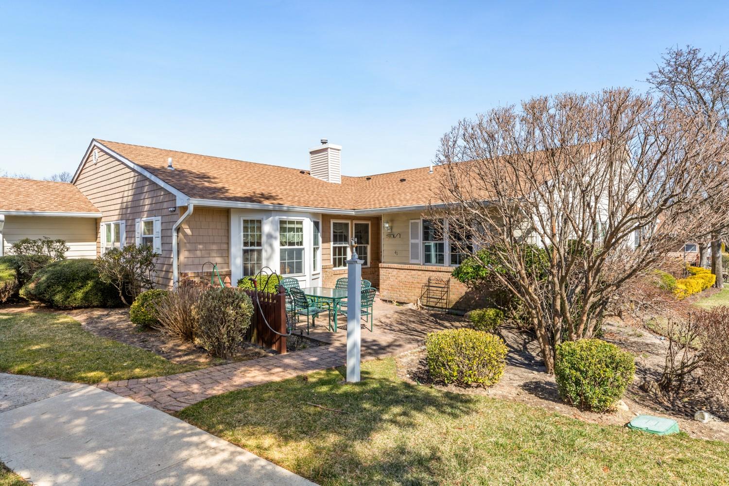 Single story home featuring a patio area, a chimney, a front yard, and roof with shingles