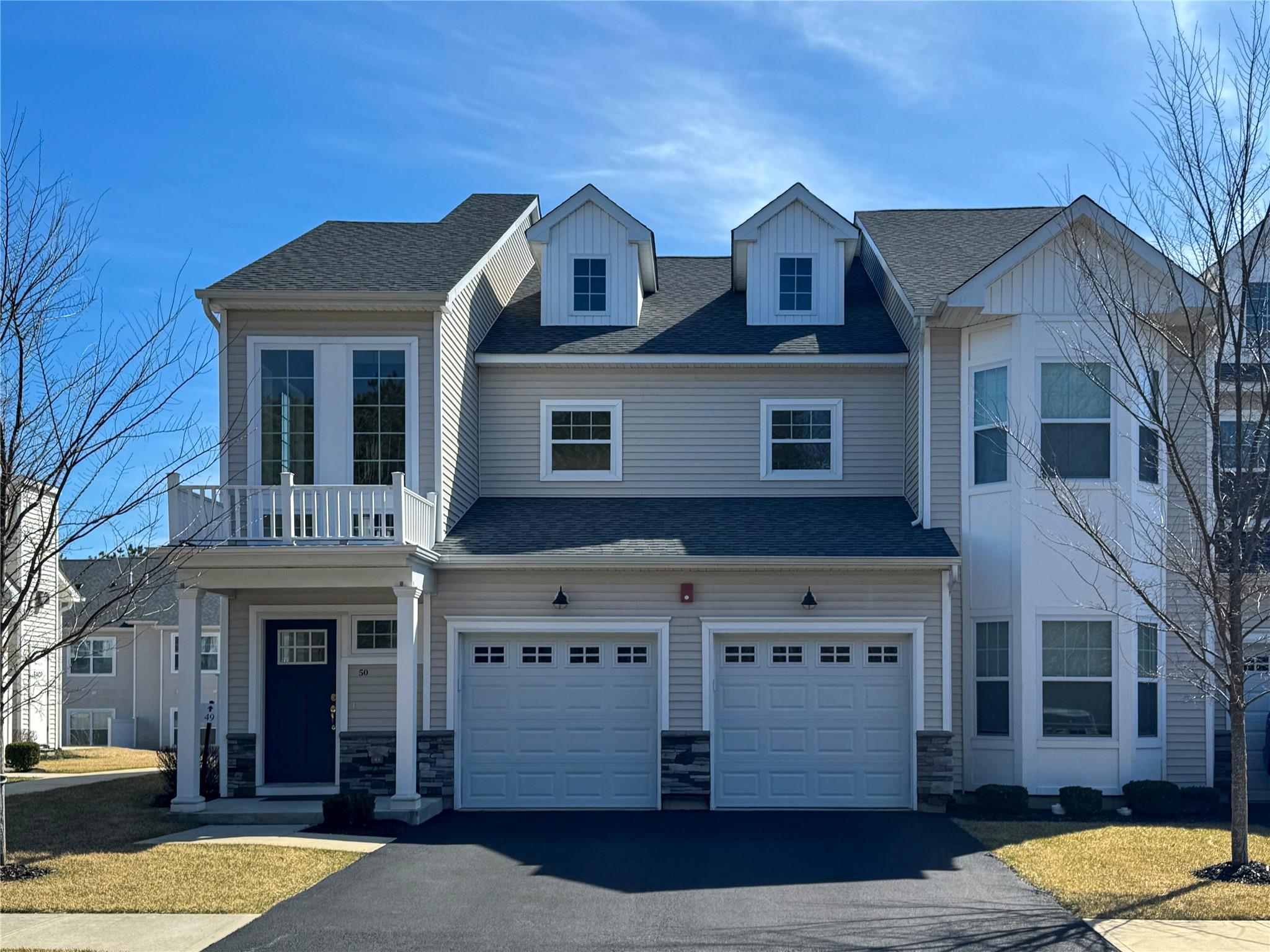 Townhome / multi-family property with stone siding, a garage, and aphalt driveway