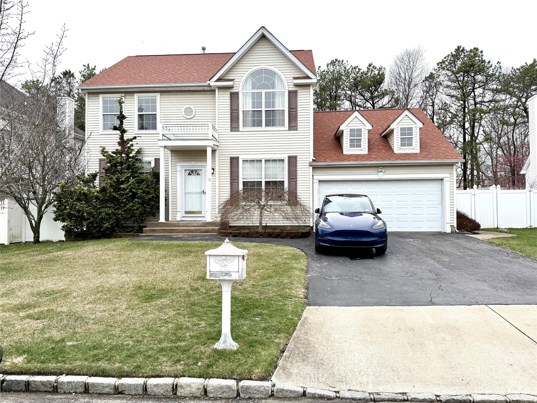 Colonial inspired home featuring fence, aphalt driveway, a front yard, a garage, and a shingled roof